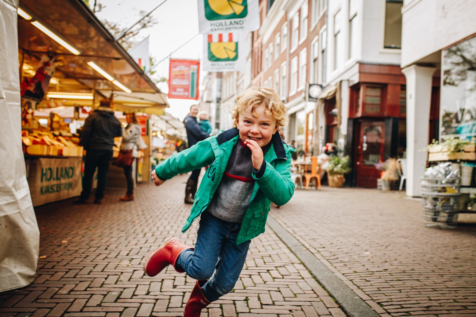 kid running towards me at the street market. He's smiling.